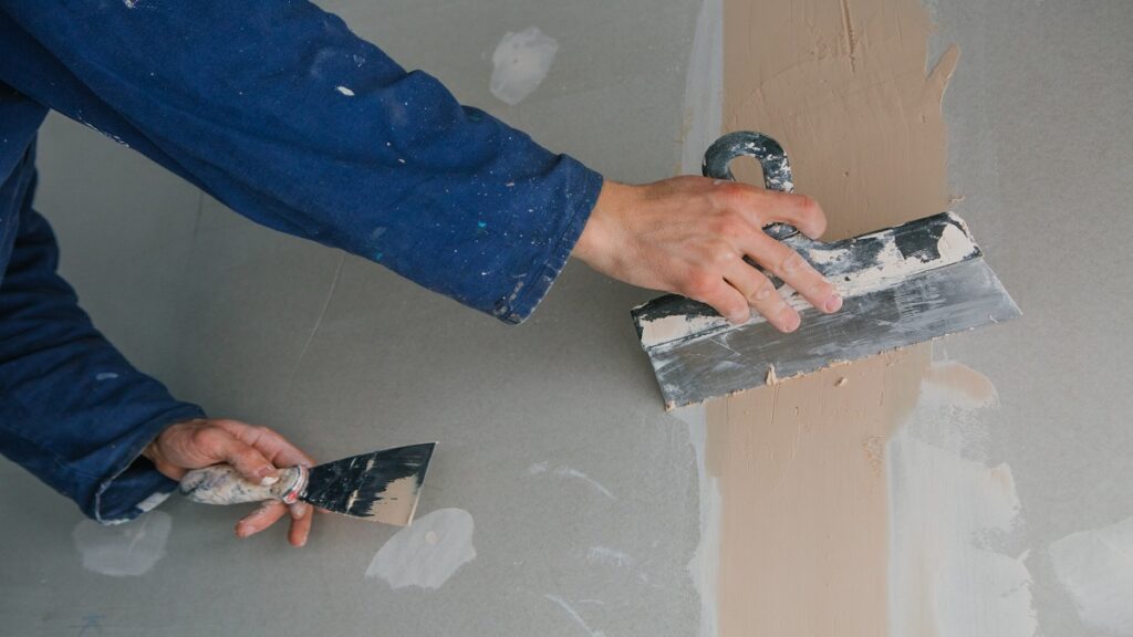 plasterer works plastering two trowels plasterboard blue uniform